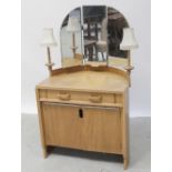 A c1960s light oak dressing table with triptych swing mirrors flanked by twin lights,