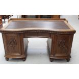 A 1930s Continental oak serpentine pedestal desk with short galleried back surmounting a shaped