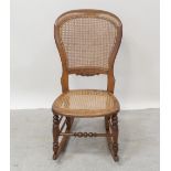 A Victorian beech spoon-back rocking chair with caned back and seat,