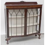 An early/mid-20th century mahogany and stained beech serpentine front display cabinet with twin