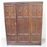 A 1930s oak triple wardrobe, the panelled doors with applied lozenges and blind fretwork detailing,