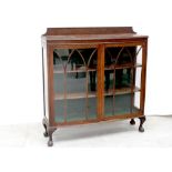 An early/mid-20th century oak display cabinet with arched glazing bars and on short cabriole legs