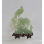 A jadeite carving on stand of an Asiatic pheasant on naturalistic rock and peony base,