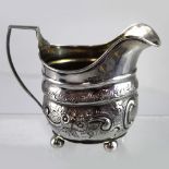 A George III hallmarked silver cream jug with later Victorian repoussé decoration to the body,