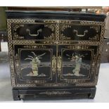 An Oriental black lacquer style side cabinet with applied shallow relief figures to a painted