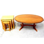A nest of three light beech occasional tables and an oval coffee table on twin pillar supports,