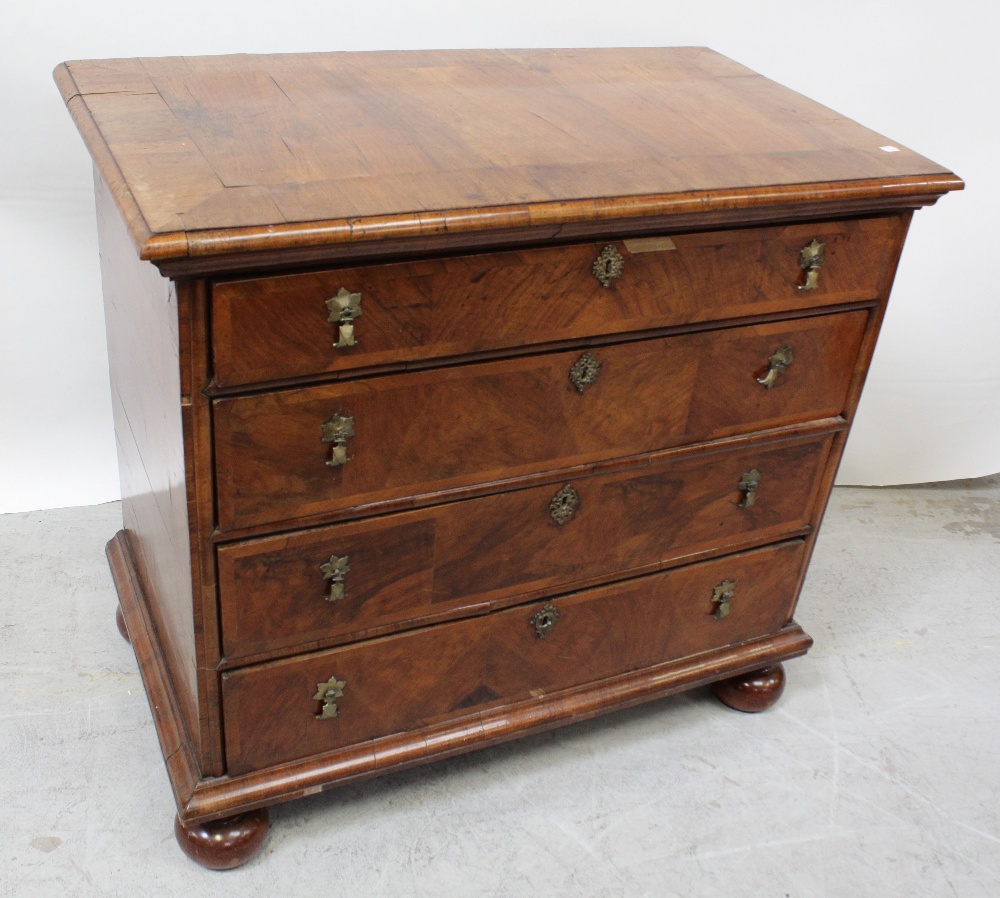 A George II cross-banded walnut chest of four graduated drawers with bifurcated brass drop handles,