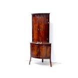 A George III mahogany two-door bow-front corner cabinet on later two-door cupboard base,