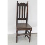 An 18th century vernacular oak high-backed hall chair with plank seat, height 113cm.