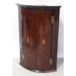 A George III mahogany two-door bow-front corner cabinet on stand,