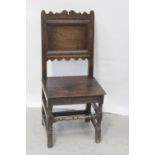 An 18th century oak panel-back hall chair with shaped top rail,