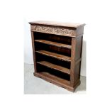 An Edwardian oak floor standing bookcase, carved frieze above two shelves to shaped plinth support,