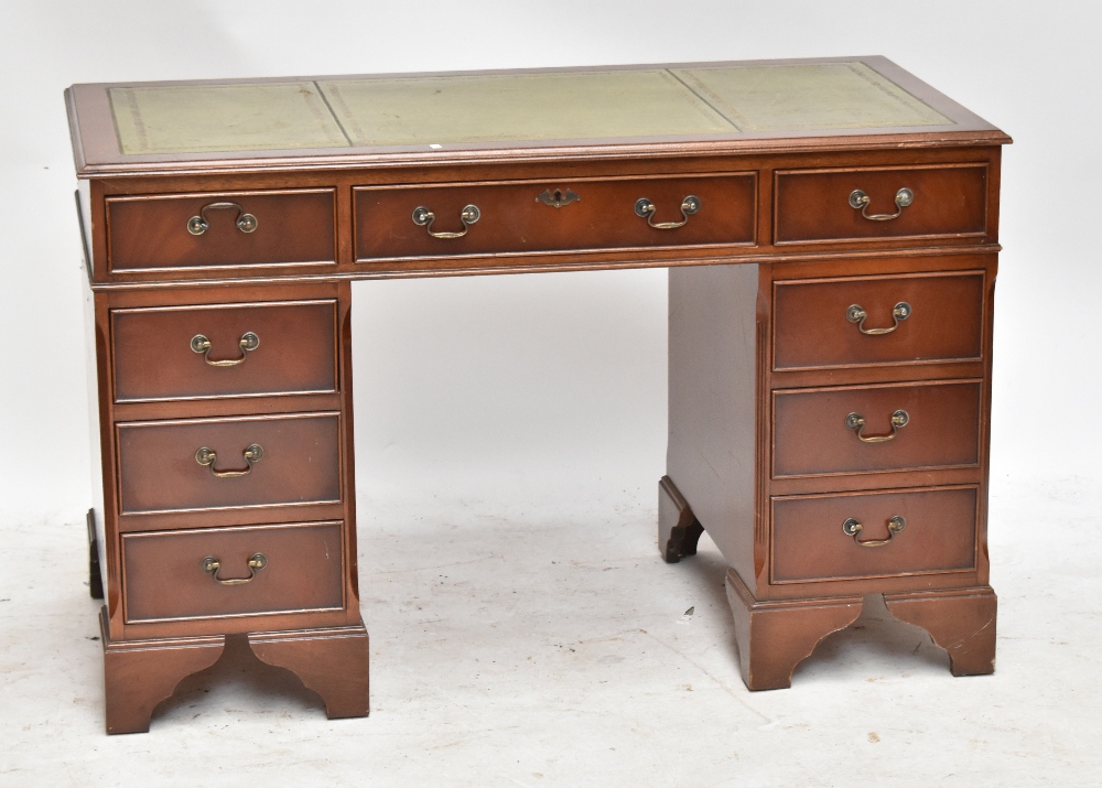 A reproduction mahogany veneered flat topped twin pedestal desk with green leather inset top with