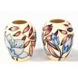 MOORCROFT; a pair of small floral tube line decorated vases on cream grounds, both with impressed