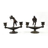 A pair of bronze twin branch candelabra, the first featuring Cupid finial (lacking bow) and the