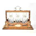 An Edwardian oak tantalus with silver plated mounts housing three hobnail cut decanters, width 44.