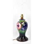 MOORCROFT; a tube line decorated 'Anemone' patter baluster lamp base on green ground and wooden