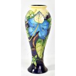 MOORCROFT; a floral tubeline decorated slender baluster vase on pale yellow and purple grounds,