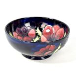 MOORCROFT; a floral tube line decorated footed bowl on navy ground, WM monogram and impressed