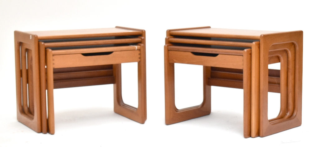 A pair of mid-century teak nest of three graduated coffee tables, each with central drawer to bottom
