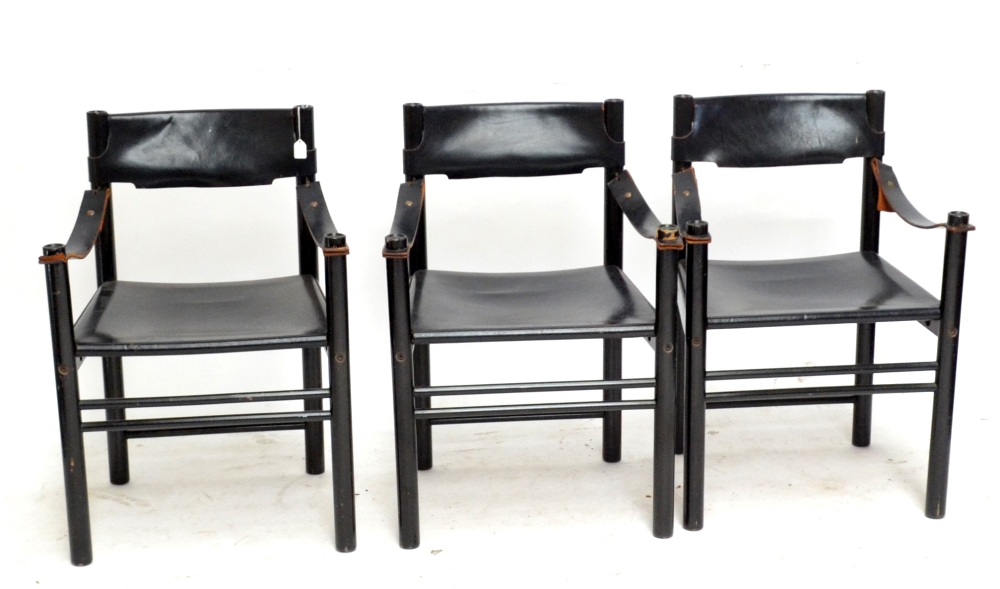 CAMEL BROWN FOR IBISCO; three black leather and black ebonised wood chairs, each raised on column