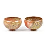 ALEX SHIMWELL (born 1980); a pair of stoneware footed bowls covered in shino and ash glaze,