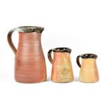 Muchelney Pottery; a graduated trio of stoneware jugs, impressed pottery marks, tallest height 28.