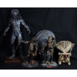 PREDATOR; a large silvered figure, height including base 63cm, two smaller figures and two masks (