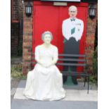 A seated figure of HRH Queen Elizabeth II on bench, width 140cm, with cardboard cutout of HRH Prince