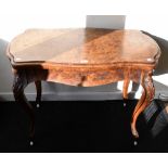 A Victorian burr walnut veneered foldover games table, raised on carved cabriole supports with