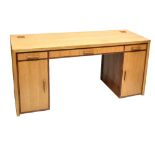 LINLEY FURNITURE; a light oak flat top kneehole desk, with three drawers above two panel cupboard