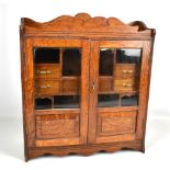 A large early 20th century oak smoker's cabinet with twin glazed doors enclosing an assortment of