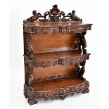 A Victorian carved walnut serpentine fronted bookcase, having four short drawers above two fixed