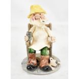 ALAN YOUNG; a pottery figure of a gentleman seated in an armchair with dog by his feet, signed