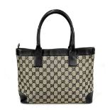 GUCCI; a monogrammed navy and cream canvas handbag trimmed with navy leather handles and base,