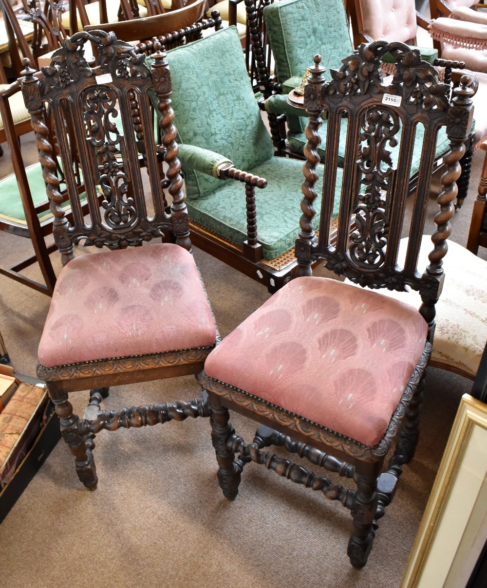 A pair of oak hall chairs with carved foliate detail throughout on stretchered barleytwist