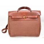 HERMÈS; a 'Herbag Ado PM' two in one maroon red leather and coated canvas backpack, shoulder or