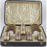 A cased set of Limoges demitasse coffee cans with hallmarked silver cradles,