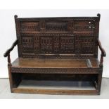 A 17th century naively carved oak settle, heavily carved back to outswept arms,