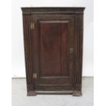 A late 18th/early 19th century oak wall-hanging corner cupboard,