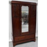 An Edwardian single mirror door wardrobe with panelled sides to one long drawer,