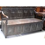 A good Edwardian oak bench settle with scrolling leaf and vine decoration to the frieze over a