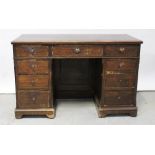An early 20th century stained pine kneehole desk with burgundy faux leather insert,
