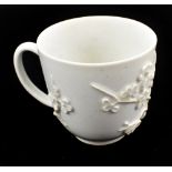 BOW; an 18th century blanc de chine coffee can with applied prunus decoration, height 5.5cm.