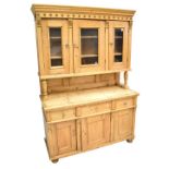 A late Victorian pine dresser, the upper section with three glazed doors enclosing two shelves on