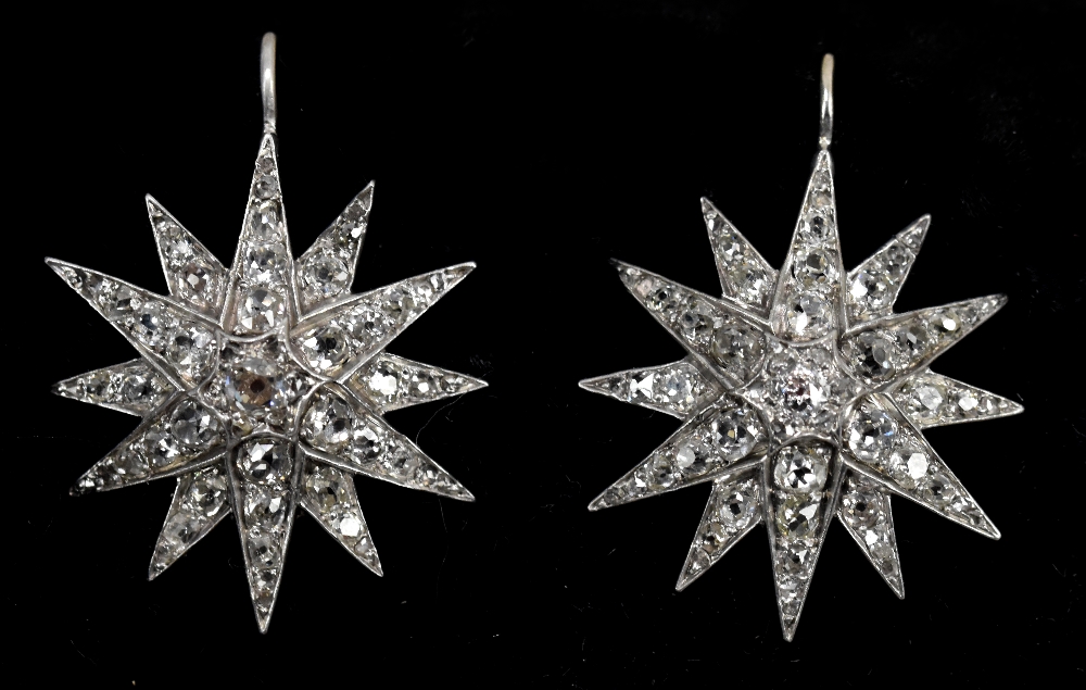 A pair of cased white metal diamond set sunburst earrings, diamond weight estimated totalling approx