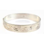 An Elizabeth II hallmarked silver hinged bangle with leaf decoration to the textured upper band,