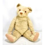 A large mid-20th century teddy bear, possibly Farnell, with blonde mohair and amber glass eyes,
