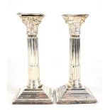 A pair of Elizabeth II hallmarked silver loaded Corinthian column candlesticks with detachable