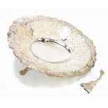 A large Eastern white metal bowl with hammered and embossed floral decoration and raised on three